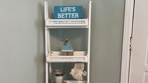 A white wooden shelf with decorative items against a light blue wall.
