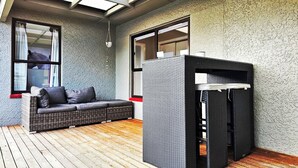 Ein Zimmer mit einem Korbsessel, einem kleinen Tisch und einer strukturierten Wand.