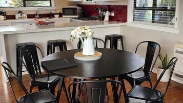 A dining area with a round table, black chairs, and a white vase with flowers.