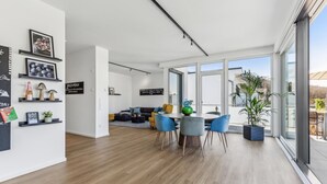 A modern living room with a dining area, large windows, and a view of the outdoors.