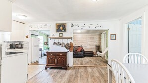 A kitchen with white cabinets, a microwave, and a refrigerator. There is a dining area with a table and chairs. - 
Lake Sweet Hut by Lake Texoma-B
 (Pottsboro)