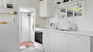 A compact kitchen with white cabinetry, a built-in oven, a sink with a modern faucet, and a window above the sink. - 2 bedroom lovely home in Jægerspris (Jægerspris)