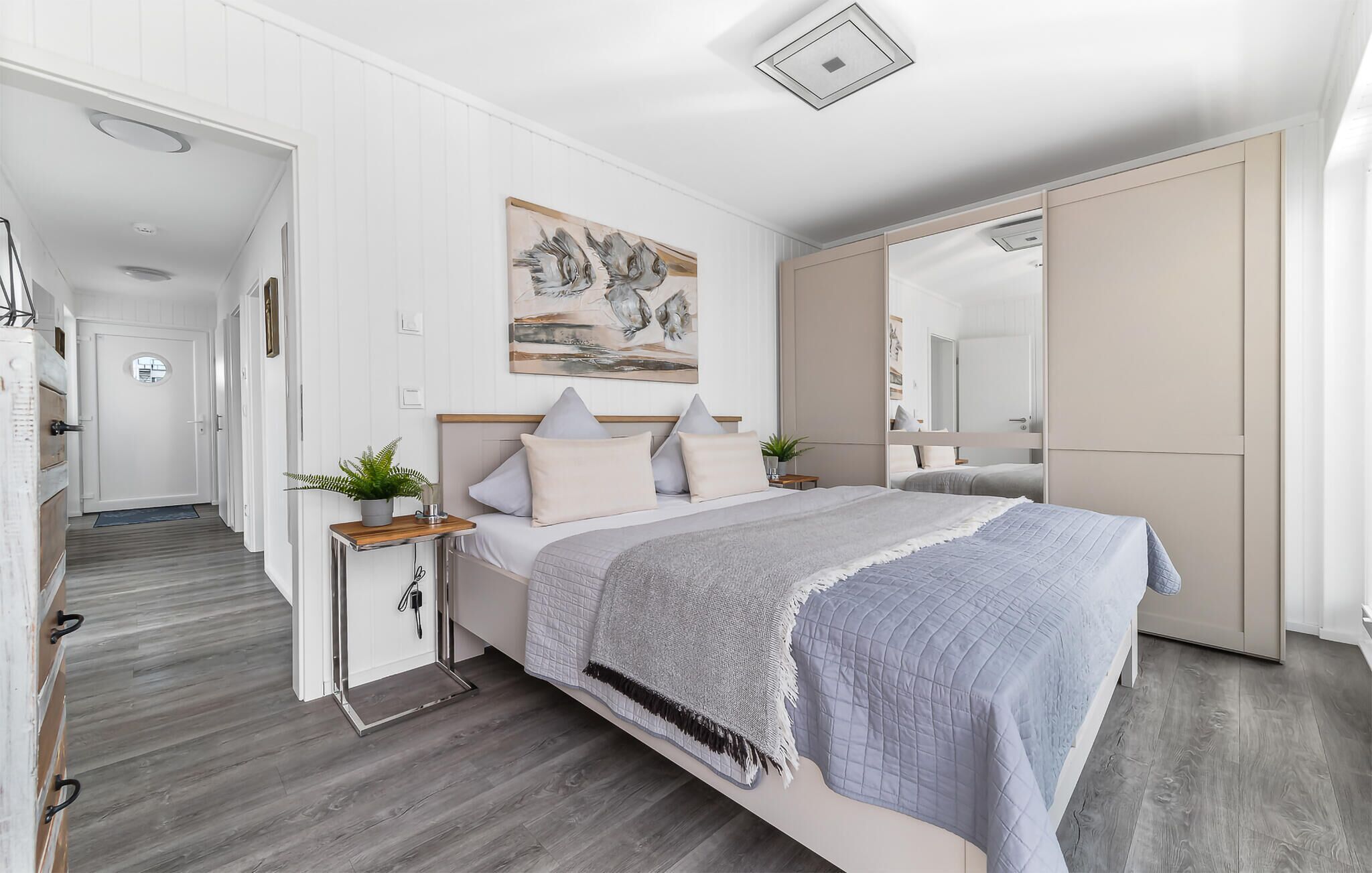 Ein modernes Schlafzimmer mit einem Bett, Nachttischen, einem Spiegel und einem Gemälde an der Wand.