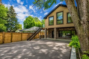 A modern two-story building with a stone facade, large windows, and a wooden fence. - Welcome to Lake House by Lis, where stunning lake views and serene sunsets await (Innisfil)