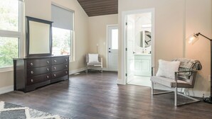 Una habitación amplia con un aparador de madera oscura, una silla blanca y una lámpara moderna.