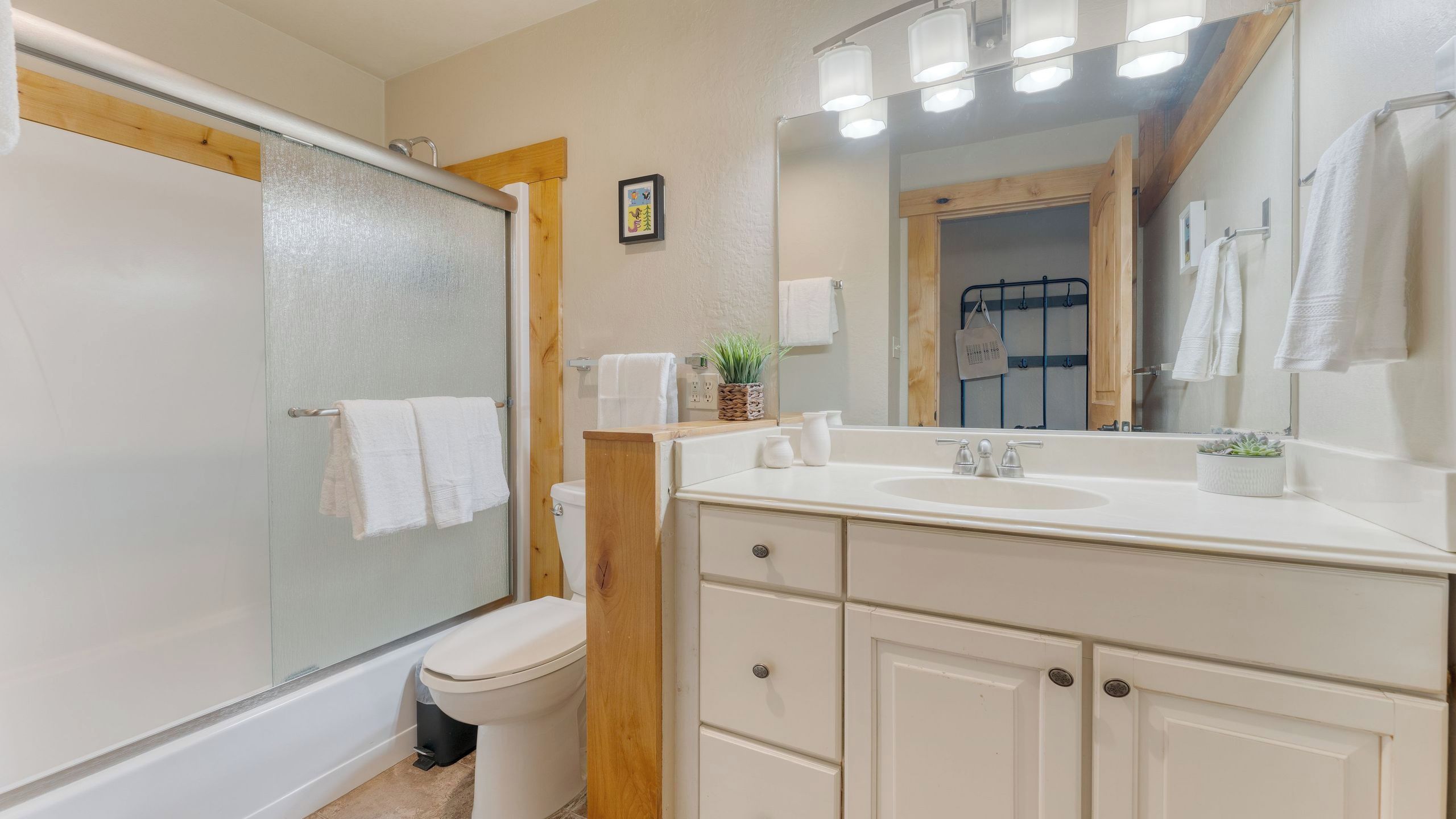 A bathroom with a glass shower enclosure, a toilet, a sink with a mirror, and a towel rack.