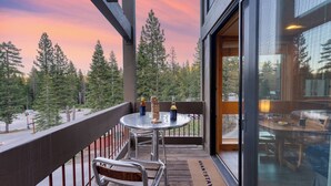 Ein Balkon mit Tisch, Stühlen und Blick auf einen Wald.