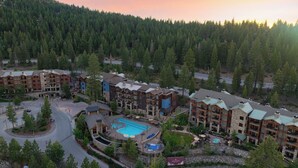 Ein Resort mit mehreren Gebäuden, einem zentralen Poolbereich und angrenzendem Wald.