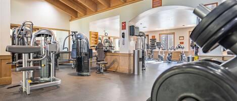 A gym with various exercise machines, a reception area, and a wooden ceiling.