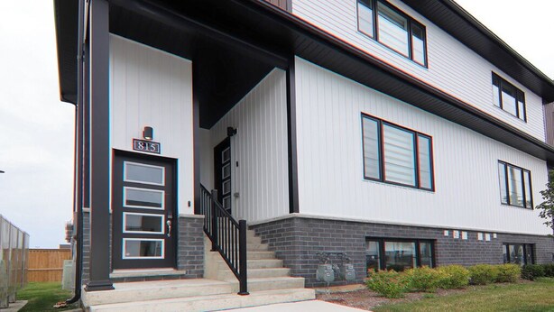 Un immeuble résidentiel moderne à deux étages, doté d’une entrée principale, d’un escalier et d’un petit jardin à l’avant.