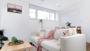 Un salon avec un canapé, une table sur laquelle est posé un plateau de cactus, une lampe et un tableau accroché au mur.
