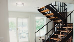 Ein modernes Interieur mit einer Holztreppe und Blick auf eine Terrasse.