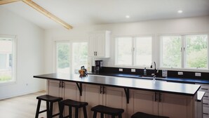 Eine moderne Küche mit einer großen Kochinsel, weißen Schränken und einem Holzbalken an der Decke.