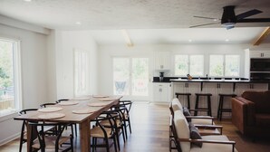 Eine geräumige Küche mit weißen Schränken, einem Holzespeisesaal mit Stühlen und einer Bar mit Hockern.