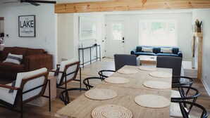 Ein modernes Wohnzimmer mit Holzboden, einem braunen Ledersofa, einem blauen Sofa und einem Esstisch mit gewebten Unterlagen.