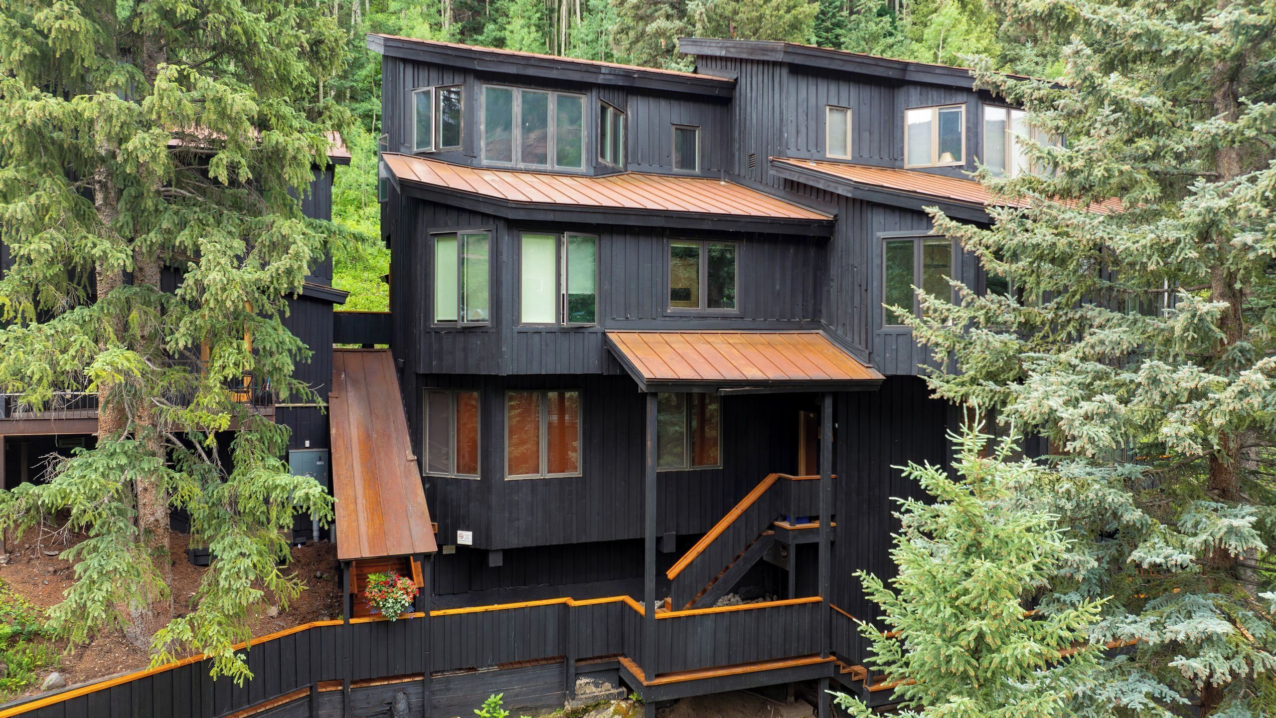 A multi-story wooden cabin with a staircase and a small deck area.