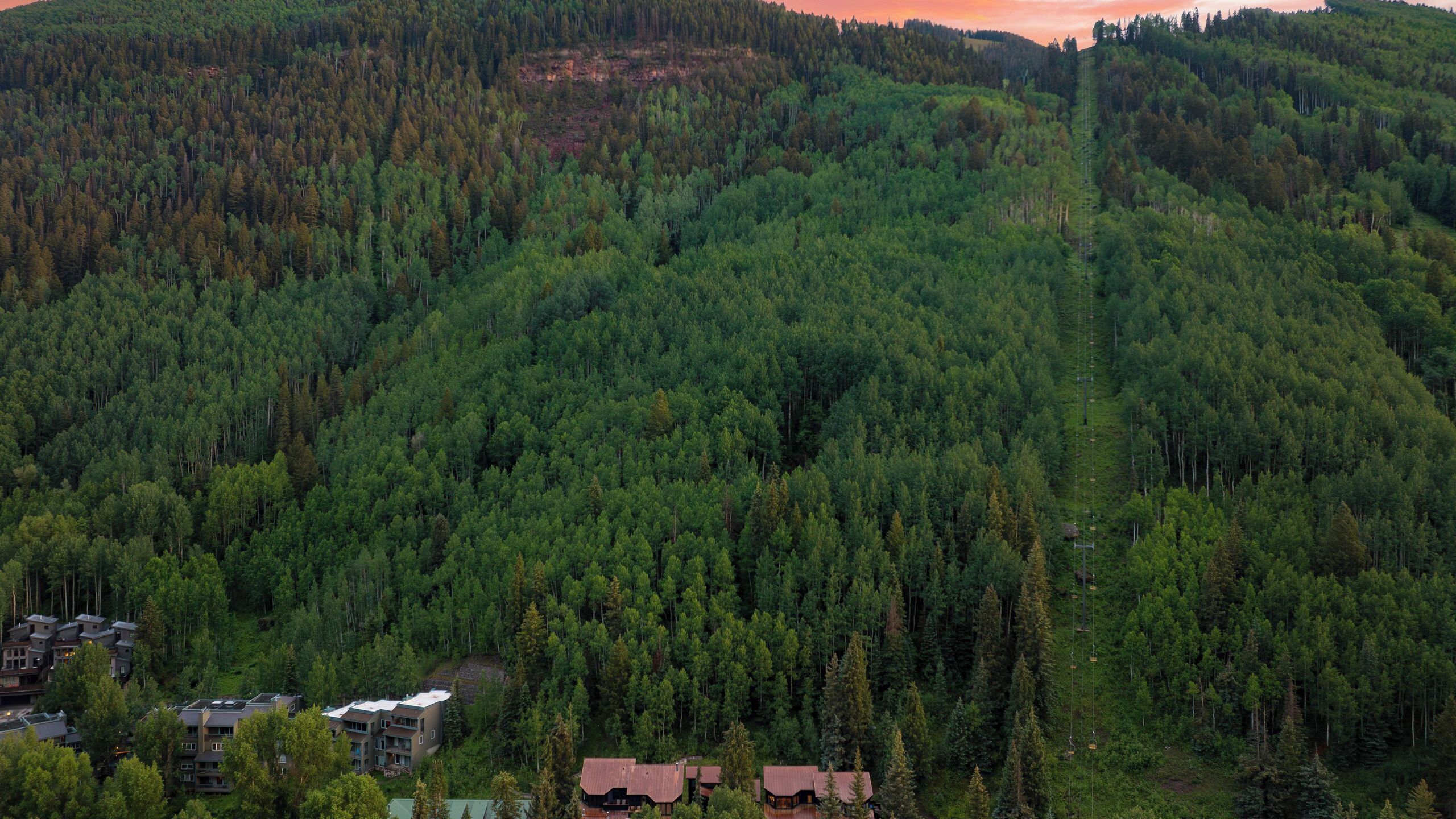Une montagne boisée, avec un petit groupe de bâtiments situés à son pied.
