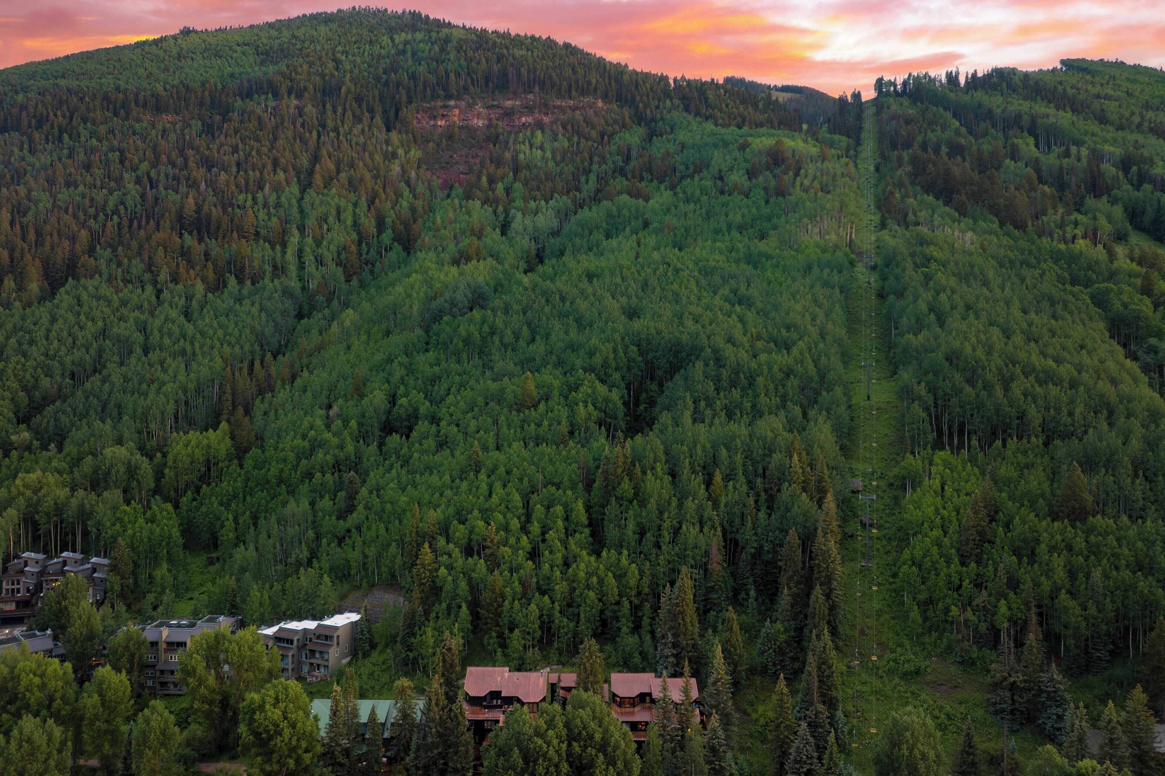 A forested mountain area with a small cluster of buildings at the base.