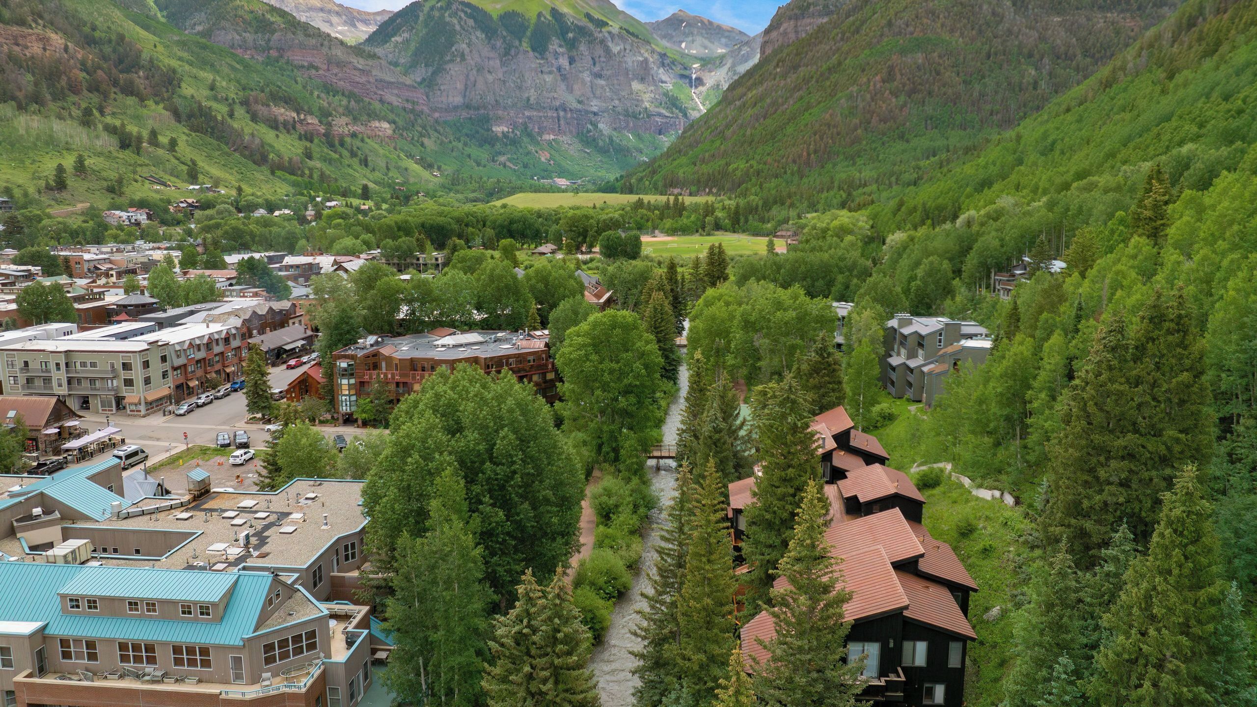 A town with buildings, a river, and mountains in the background.