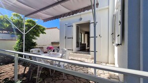 A patio with a table and chairs, a covered area, and a building entrance. - Saint Georges de Didonne - IDEAL NEIGHBOURHOOD FOR RESOURCE - RENOVATED HOUSE (ST GEORGES DE DIDONNE)