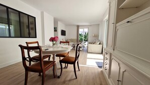 A spacious dining area with a round table and wooden chairs, a living area with a sofa and a TV, and a large wardrobe with a keyhole. - Saint Georges de Didonne - IDEAL NEIGHBOURHOOD FOR RESOURCE - RENOVATED HOUSE (ST GEORGES DE DIDONNE)