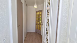 A narrow hallway with a wooden floor, white walls, and a door with a decorative glass panel. - Saint Georges de Didonne - IDEAL NEIGHBOURHOOD FOR RESOURCE - RENOVATED HOUSE (ST GEORGES DE DIDONNE)