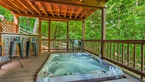 Un bain à remous sur une terrasse en bois, avec vue sur une forêt.