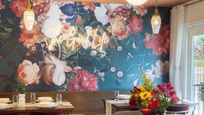 A restaurant interior with a floral mural, a neon sign, a bar area, and a counter with food and drinks. - Omaha Oasis! Pool, Hot Tub, Mini Golf, Bar, Games (Omaha)