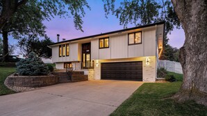 A modern two-story house with a garage, a well-maintained lawn, and a large tree. - Omaha Oasis! Pool, Hot Tub, Mini Golf, Bar, Games (Omaha)