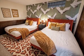 A hotel room with two beds, a patterned rug, wall art, and a mural of birds. - Omaha Oasis! Pool, Hot Tub, Mini Golf, Bar, Games (Omaha)