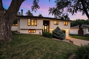 A two-story house with a front door, windows, and a chimney. - Omaha Oasis! Pool, Hot Tub, Mini Golf, Bar, Games (Omaha)