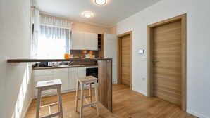 A compact kitchen with white cabinets, a wooden countertop, and two stools. - 2 bedroom cozy home in Margecan (Margecan)