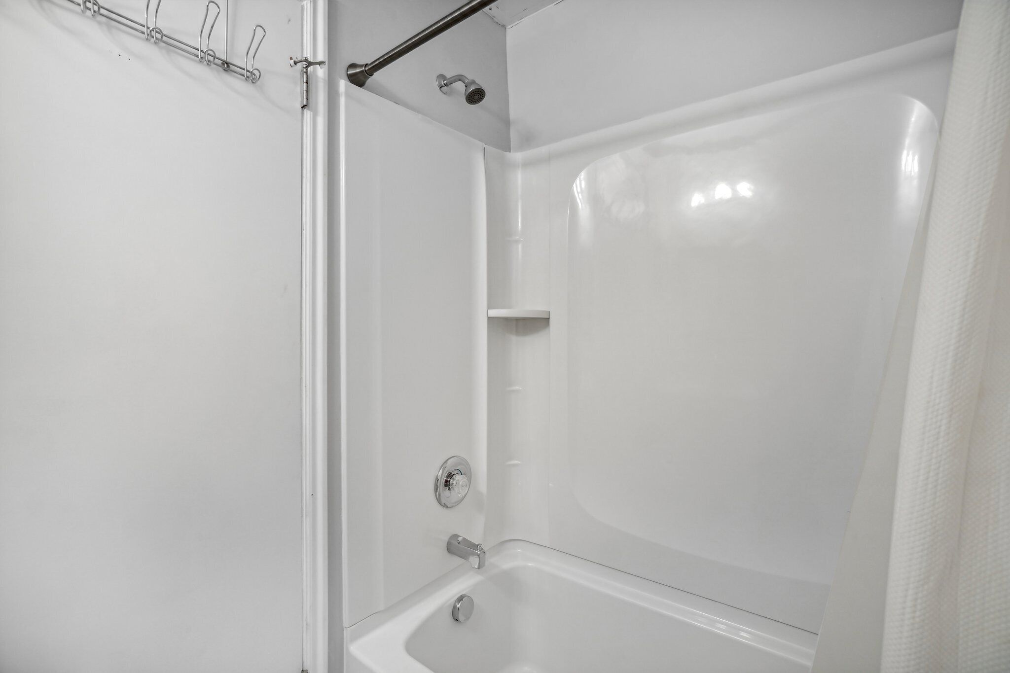 Een moderne badkamer met een bad, douche en handdoekrek.