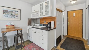 A compact kitchen with white cabinets, a microwave, a coffee maker, and a small dining area with stools. - Comfortable Studio in the Heart of Park City (Park City)