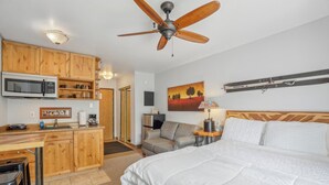 A compact hotel room with a kitchenette, a bed, a ceiling fan, and a painting on the wall. - Comfortable Studio in Park City 325 (Park City)