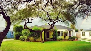 A residential house with a well-maintained lawn, a large tree in the front yard, and a neighboring house. - Private Detached Cottage ~Near Downtown Phoenix! (Phoenix)