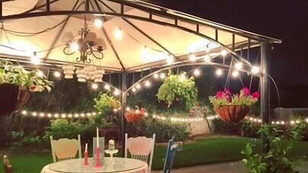 An outdoor patio with a round table, chairs, hanging plants, and string lights. - Private Detached Cottage ~Near Downtown Phoenix! (Phoenix)