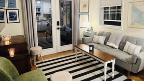 Ein Wohnzimmer mit Streifenmuster-Teppich, einer Couch, einem Couchtisch und einem Esstisch.