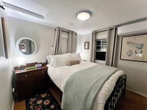 A neatly arranged bedroom with a bed, bedside table, lamp, and a framed picture on the wall. - Camano Island Cottage - Madrona Beach (Camano Island)