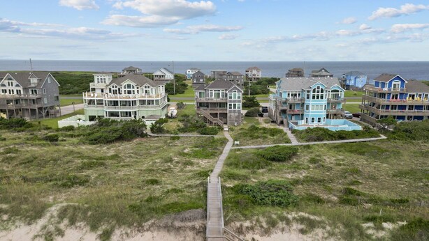 A coastal residential area with beachfront houses, a wooden boardwalk, and a sandy beach. - 7865- Peridot, Oceanfront 5 bedroom home in Frisco! (Frisco)