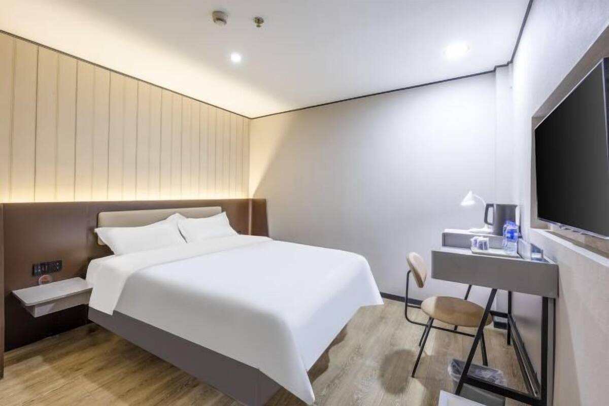 Et moderne hotelværelse med en stor seng, et skrivebord med stol og et fladskærms-tv.