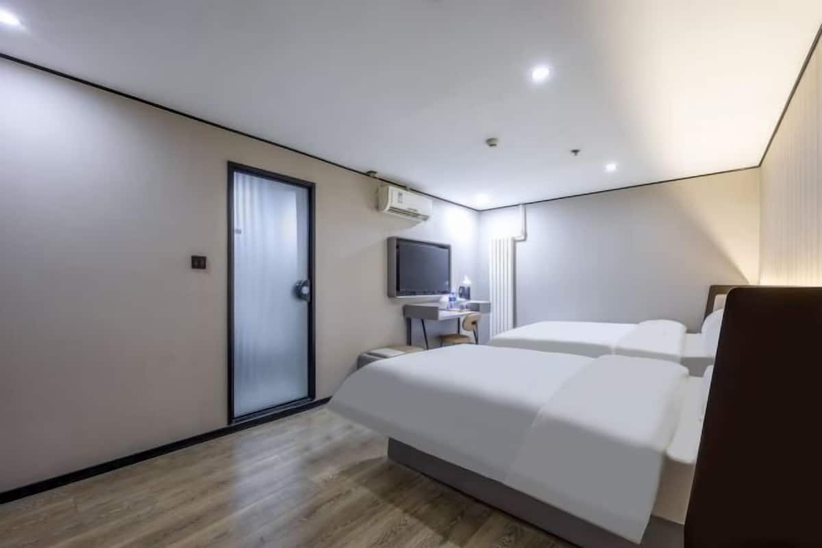 Et hotelværelse med seng, skrivebord, stol, fjernsyn og aircondition.