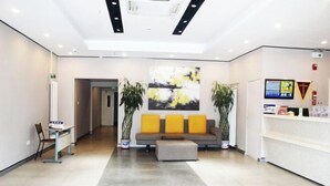 A modern reception area with a sofa, two potted plants, and a digital screen. - Taishangdeng Hotel (Beijing Daxing Huangyi Road Public Security University Branch) (Beijing)