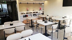 A modern restaurant with white tables and chairs, a counter with various items, and a wall-mounted TV. - Taishangdeng Hotel (Beijing Daxing Huangyi Road Public Security University Branch) (Beijing)