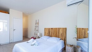 A modern hotel room with a large bed, a wooden headboard, a small side table, and a wardrobe. - Studio de la Villa 2 étoiles - Welkeys (Bandol)
