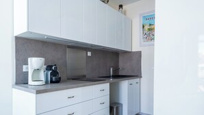A modern kitchen with white cabinets, a stainless steel sink, and a coffee machine. - Studio de la Villa 2 étoiles - Welkeys (Bandol)