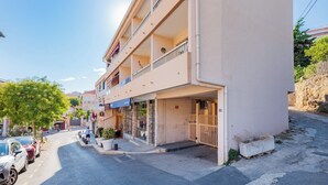 A multi-story hotel with balconies, a ground-level entrance, and a parking area. - Studio de la Villa 2 étoiles - Welkeys (Bandol)