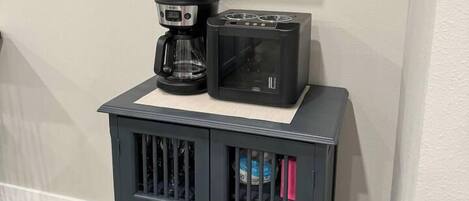 A kitchenette with a coffee maker, toaster, and a small shelf above.