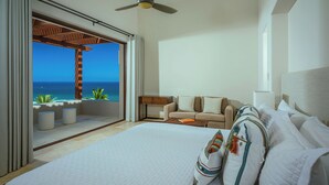 A hotel room with a large bed, a sofa, and a view of the ocean.