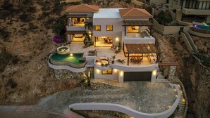 A modern two-story house with a swimming pool, outdoor seating, and a garage.